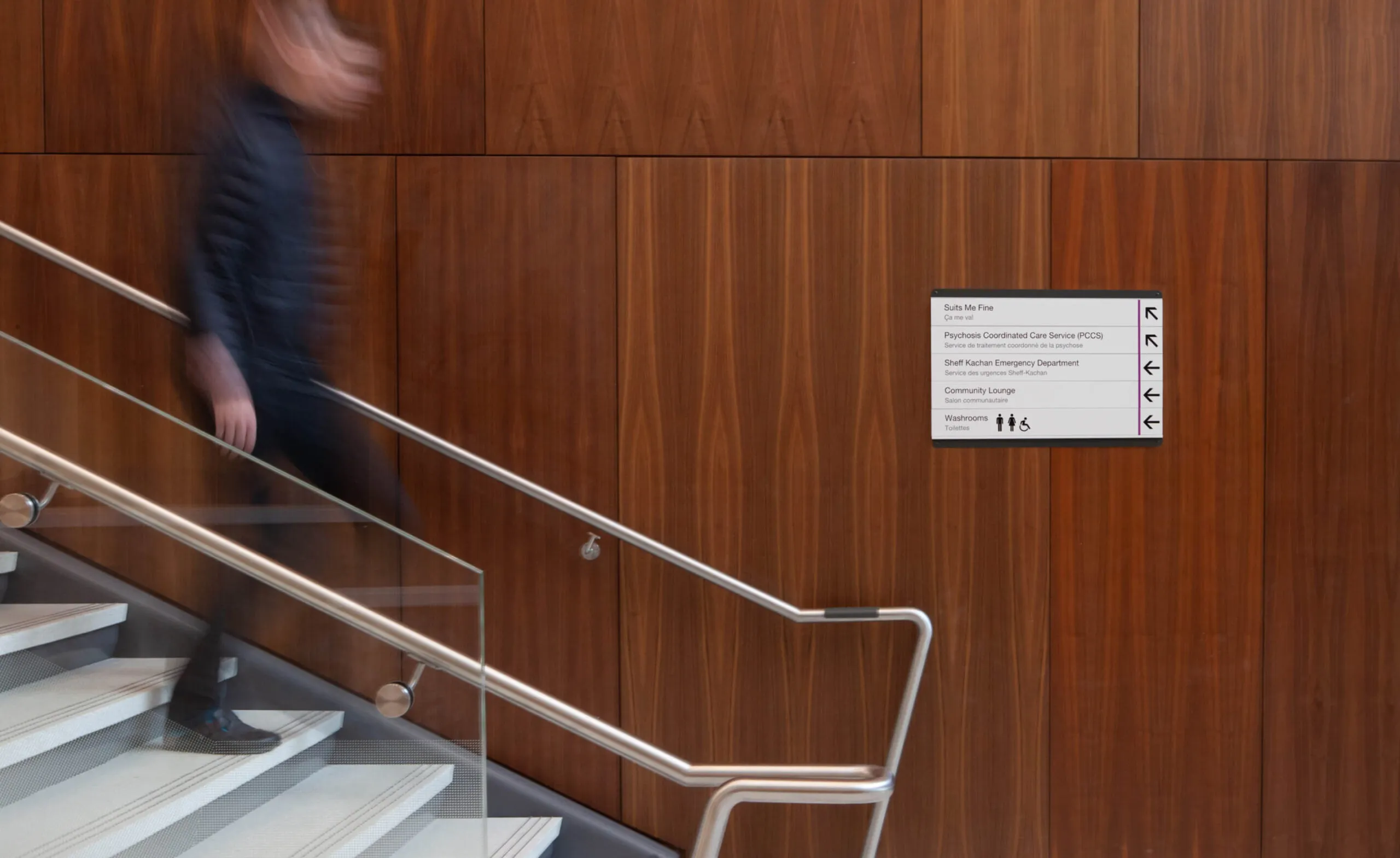 Person walking down stairs next to a directory sign at CAMH.