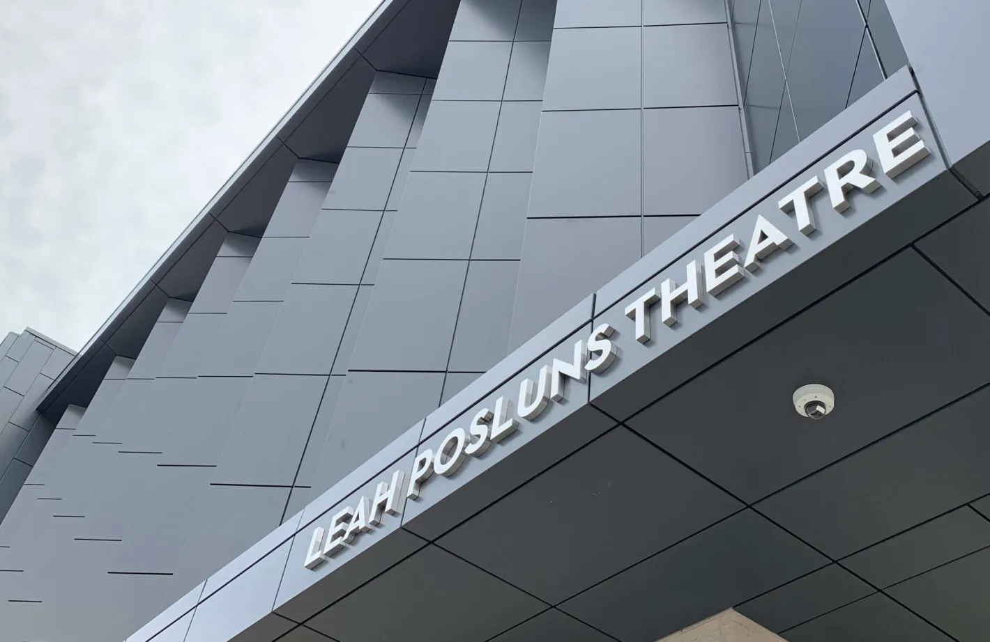 Leah Posluns Theatre sign on a modern building with a security camera.
