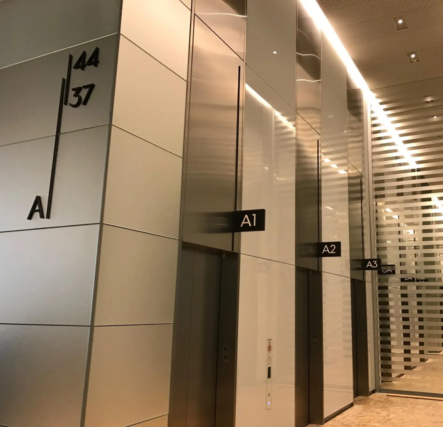 Elevator bank with signs A1, A2, A3 and floor numbers 44 and 37.