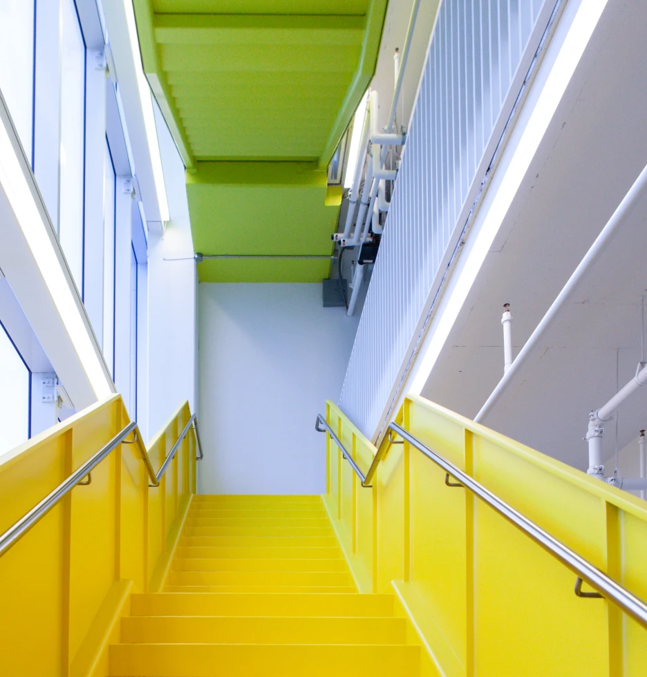 Bright yellow staircase with green ceiling and large windows.