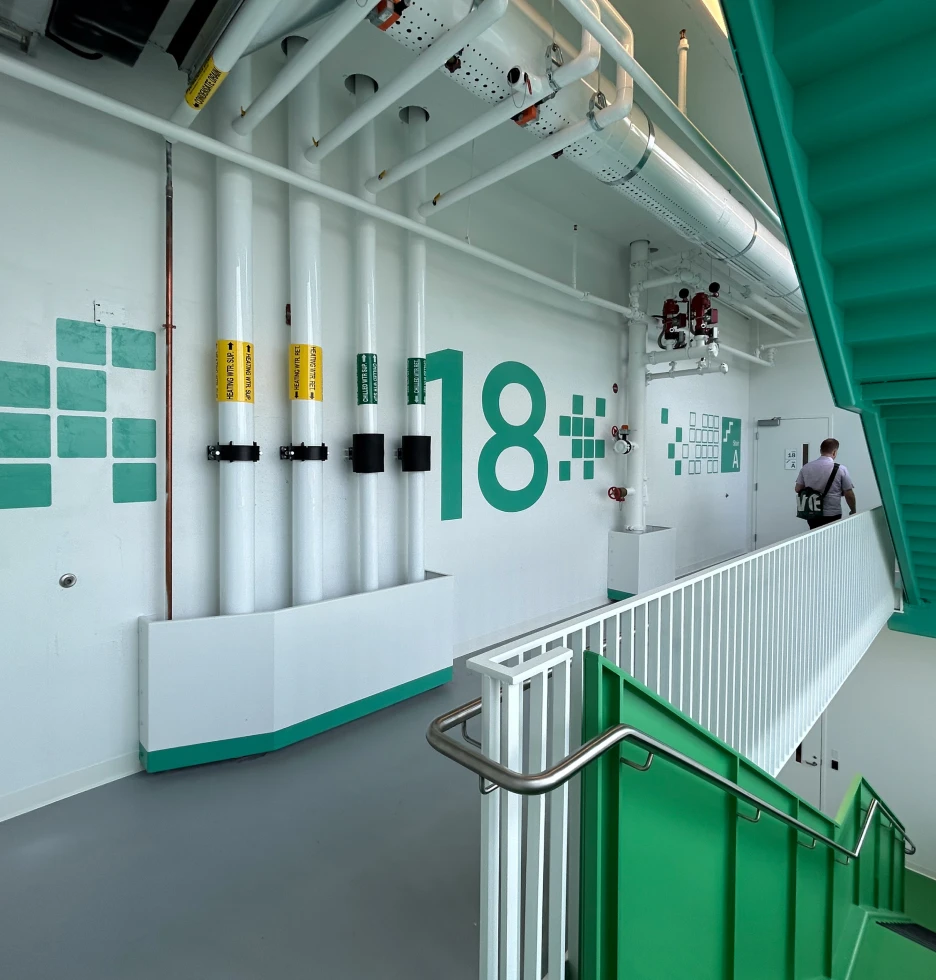 Interior view of a modern hallway with green accents and large number 18 on the wall.
