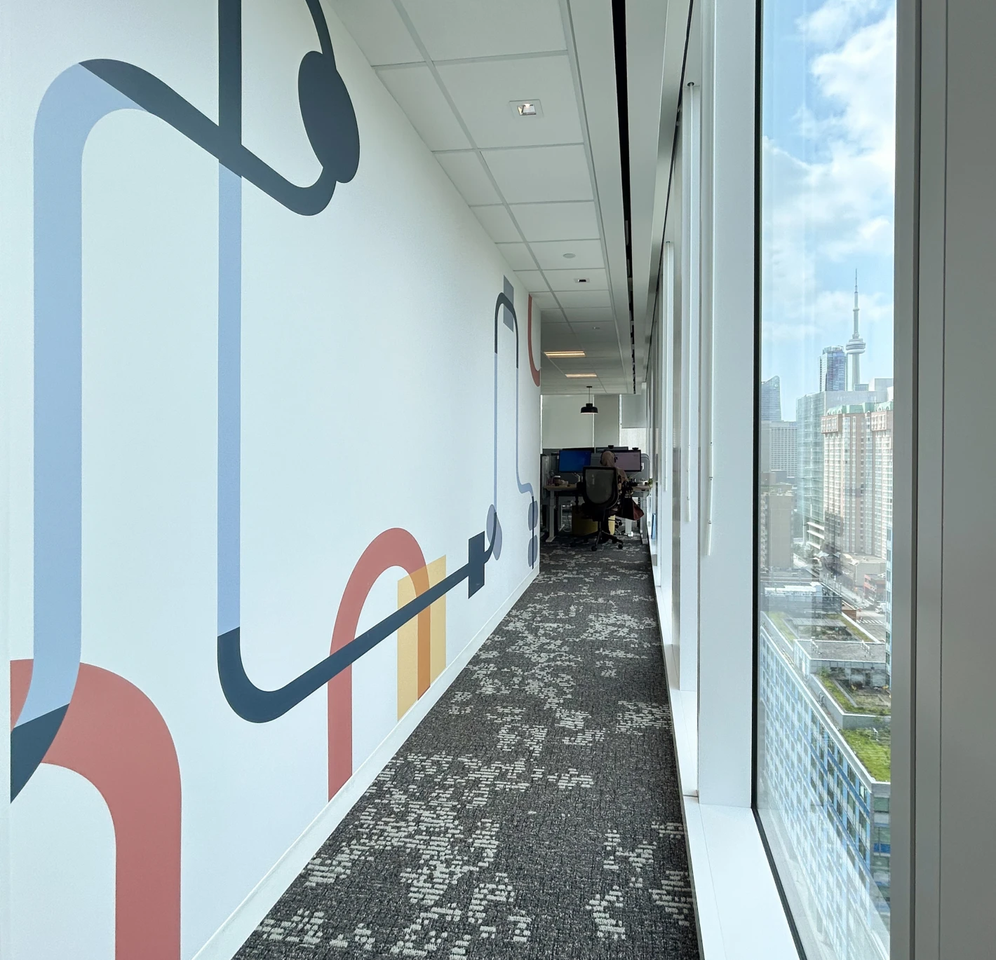 Modern office hallway with abstract wall art and city view.