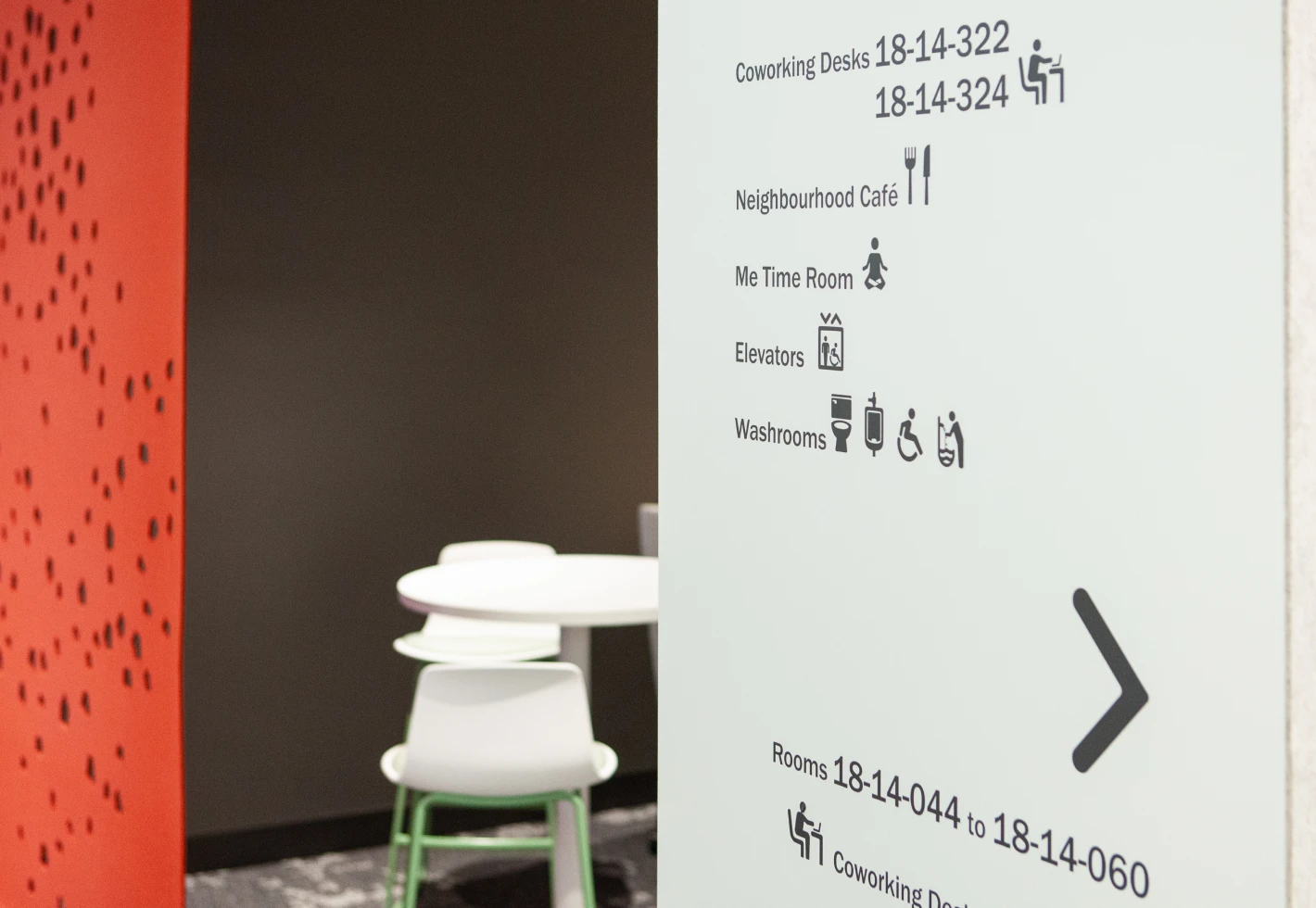 Signage with room numbers and icons for coworking desks, cafe, me time room, elevators, and restrooms.