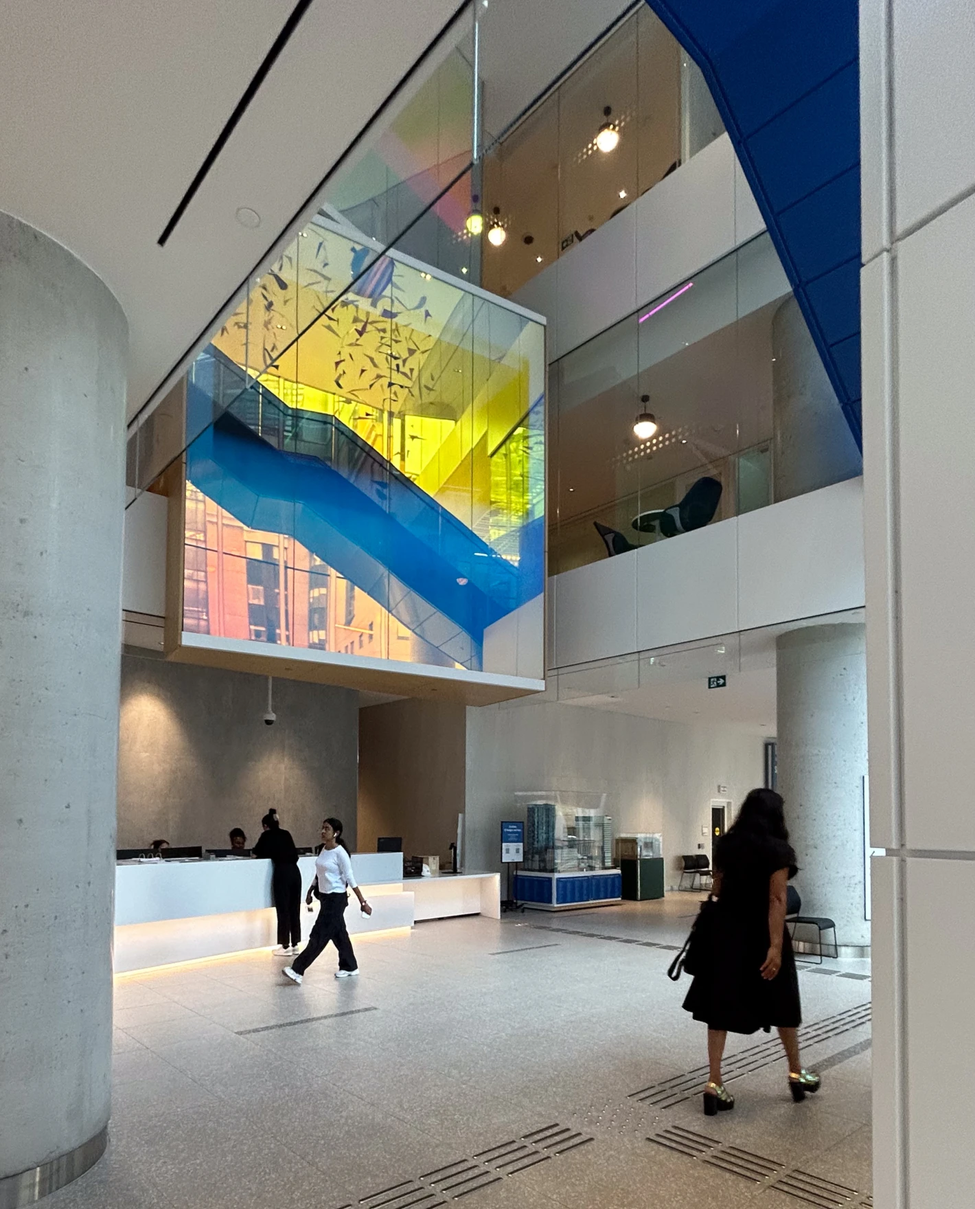 Modern interior with colourful glass staircase and people walking.