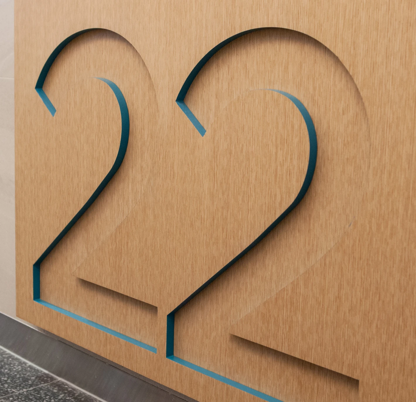 Close-up of the number 22 carved into a wooden surface with blue accents.