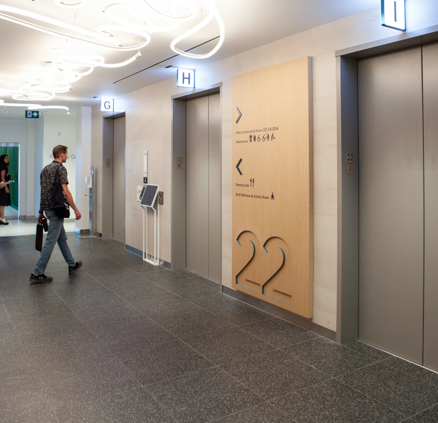 Modern office hallway with elevators and directional signage.